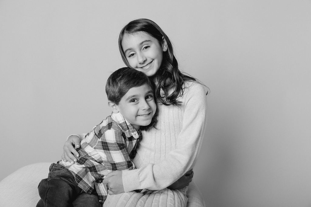 Black-and-white studio hug between siblings