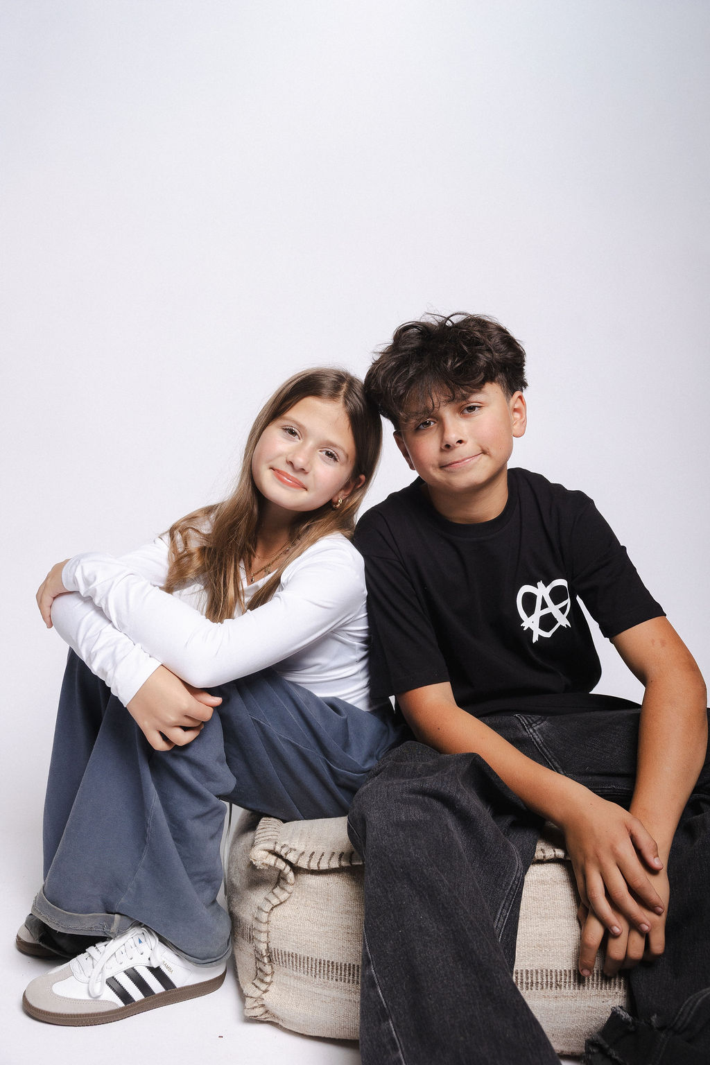 Siblings on a floor cushion in studio
