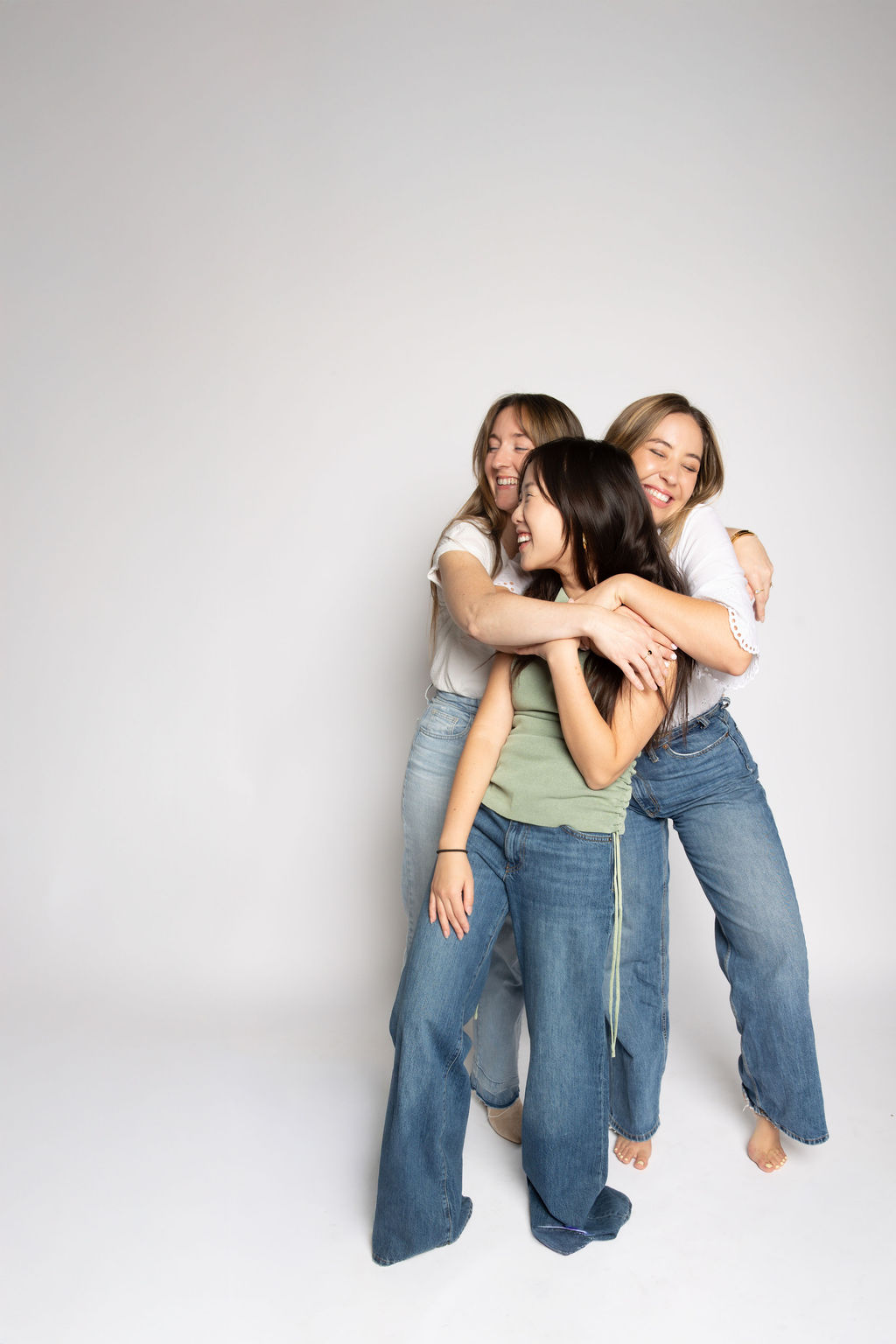 Three friends in a studio group hug