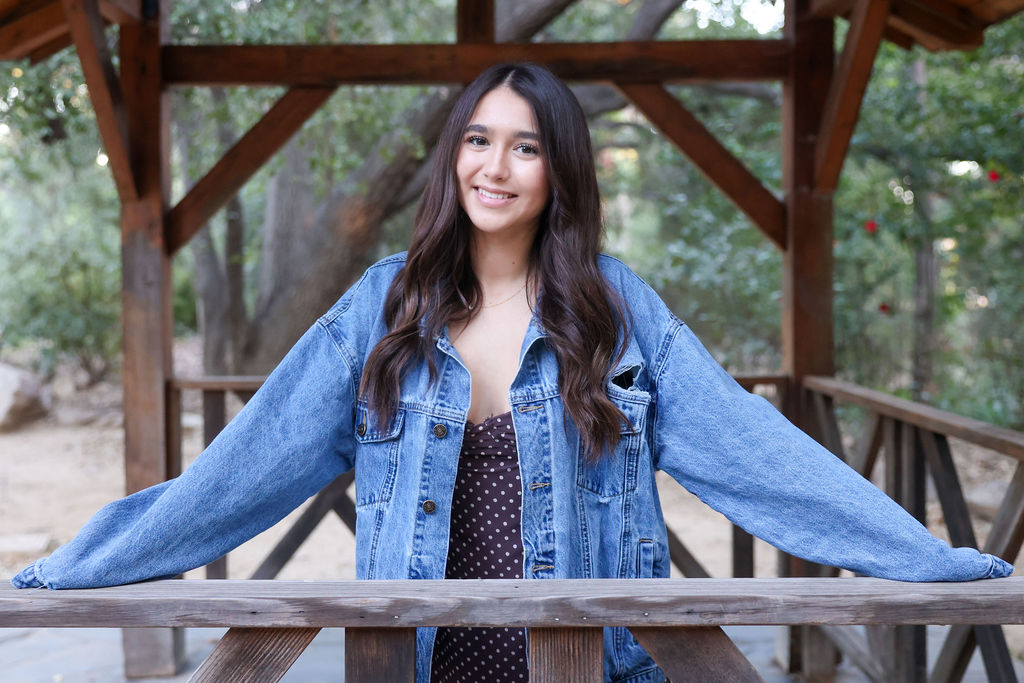 Outdoor portrait in a denim jacket, hands on a wooden pavilion rail