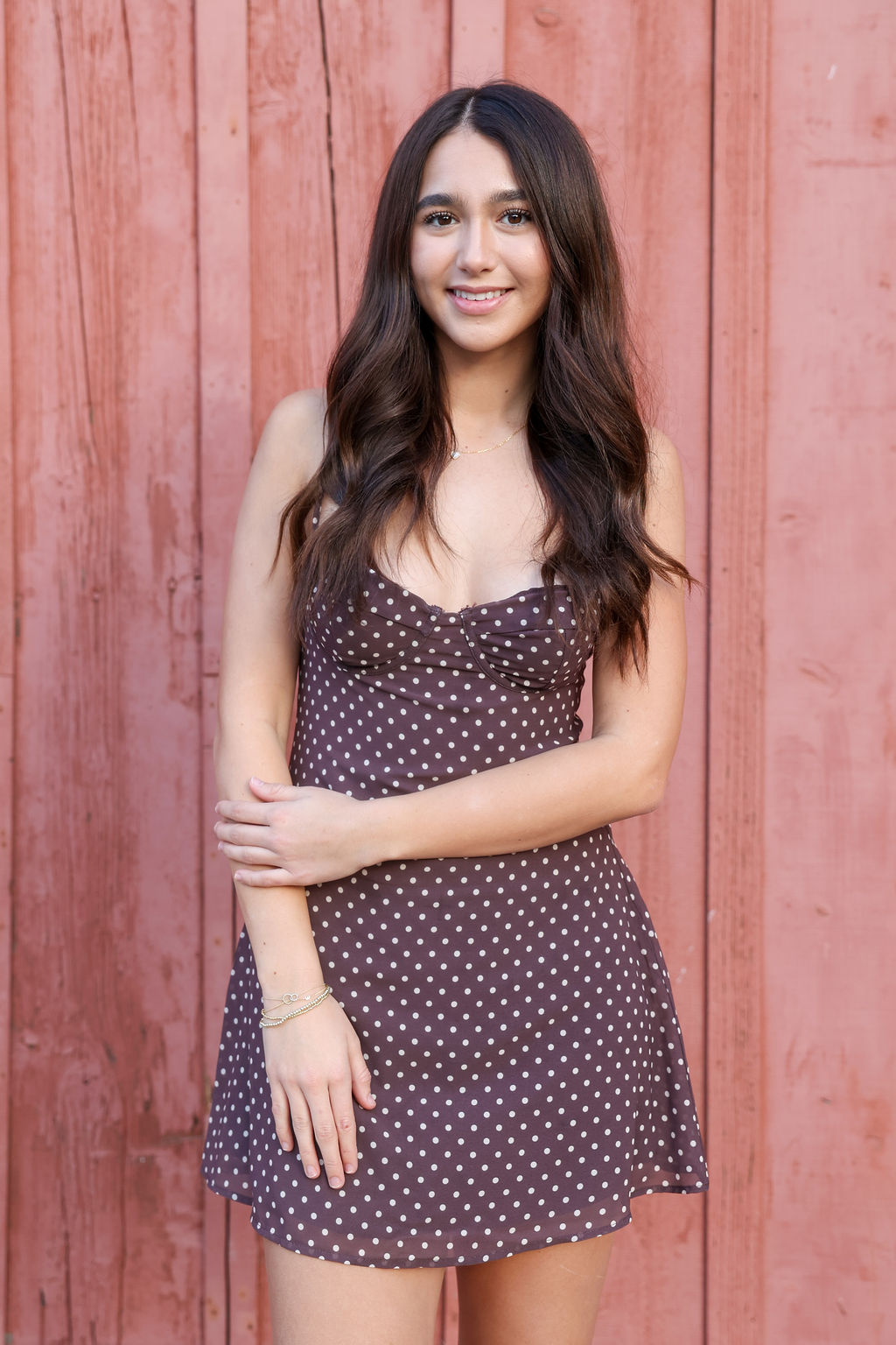 Portrait in a polka-dot mini against a red wall